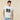 A model wearing a Rowing Blazers Open Weave Sweater Jersey Cream, a white, linen-cotton blend V-neck sweater with short sleeves, an open-weave knit, the number 99 in black on the chest, and a circular emblem on the lower front.