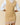 A Rowing Blazers Women’s Cotton Blend Cable Dress Camel featuring a sleeveless tan V-neck design worn over a white collared shirt with a red and white striped hemline.