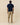 A man viewed from behind, wearing a Rowing Blazers x Winnie-the-Pooh Men’s Short Sleeve Eeyore Pique Polo Navy, khaki trousers, and white sneakers.