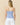 Back view of a Women’s Cotton Poplin Pinstripe Top Bright Blue Stripe worn with white shorts featuring embroidered graphics.
