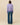 Woman wearing a purple sweater with sheep pattern and blue jeans on a beige background