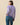 Woman wearing a purple sweater with sheep pattern on a beige background