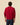 A person seen from the back, wearing a red Men’s Cotton Cable Sheep Sweater Burgundy and dark trousers.