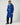 A man wearing a royal blue wool Rowing Blazers x Paddington™ Paddington Duffel Coat with a hood, toggle closures, and a circular patch on the left sleeve.