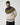 A smiling man wears a black Derry Bones Santa Beanie and a cream-colored zip-up sweater featuring a blue and yellow patterned yoke.