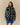 A person wearing a forest green Warm & Wonderful Sheep Sherpa Jacket with a repeating white sheep pattern and zip-up front.