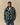 A person wears a dark green Warm & Wonderful Sheep Sherpa Jacket patterned with repeating white sheep figures and featuring a zip-up front.