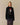 A black Paddington Tuxedo Wool Sweater featuring an intarsia knit graphic of a bear in a tuxedo and a red hat.