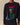 A person wears the Rowing Blazers x Babar Babar in New York Cotton Sweater Navy, featuring Babar as the Statue of Liberty holding an American flag with BABAR à New York above.