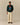 A man wears a dark green, cashmere-blend Rowing Blazers x Paddington™ Paddington Cashmere Sweater Green crewneck featuring a colorful Paddington motif of the bear holding a jar of marmalade.