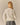 Back view of a person wearing a long-sleeved cream Penelope Paddington Cashmere Sweater Ivory and a black and white houndstooth pleated skirt.