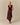 A model wears a burgundy Paige U-Neck Corduroy Top with a deep U-neck and a plaid, fringed asymmetrical midi skirt.