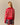 A woman with long blonde hair, seen from behind, wears the Warm & Wonderful Diana Edition Cotton Linen V-Neck Sheep Sweater Red and a short, pleated plaid skirt.